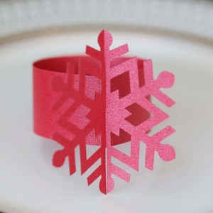 Macro detail of red glitter snowflake napkin ring on a white ceramic plate