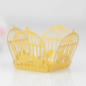 Detailed laser-cut bright yellow paper cupcake wrapper with intricate birdcage patterns