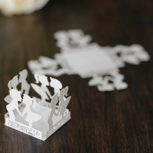 White laser-cut wedding candy gift box with romantic couple silhouette on dark wood