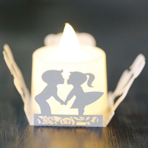 Macro view of white paper cut candle shade with romantic boy and girl silhouettes