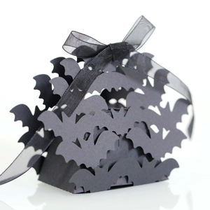 Detail of laser-cut black Halloween candy box with bat patterns and organza ribbon