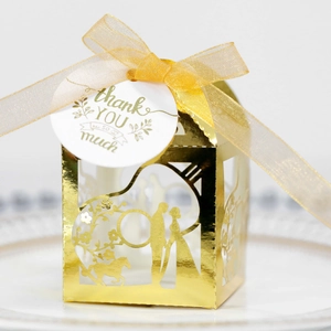 Détail de la boîte à bonbons de mariage dorée découpée au laser avec calèche et étiquette