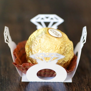Macro detail of white laser-cut ring-shaped wedding favors box with hollow patterns