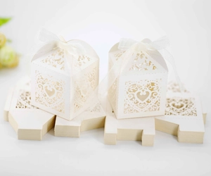 Detailed view of cream laser-cut heart favor boxes with elegant white silk ribbons