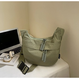 Detail view of green nylon crescent bag featuring woven zipper and adjustable buckle strap