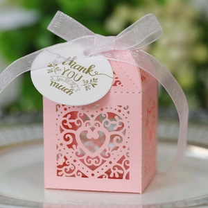Pink laser-cut wedding favor box with heart pattern and white thank you ribbon