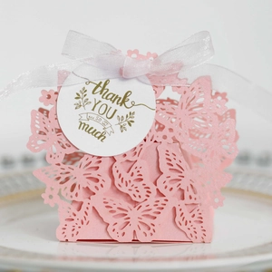 Detail of pink laser-cut butterfly candy box with a gold thank you tag and white ribbon