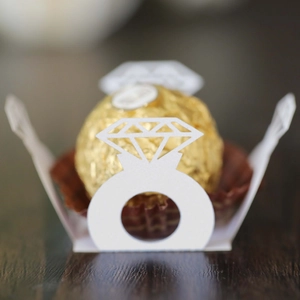 Macro detail of white laser-cut diamond ring candy holder with gold foil chocolate