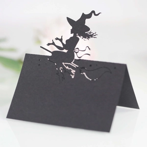 Laser-cut black paper place card with Halloween witch on broomstick silhouette design
