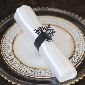Close-up of black snowflake napkin ring on white silk napkin for festive table decor