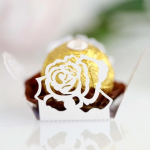 Makroaufnahme von lasergeschnittenen weißen Rosenmustern auf Schokoladenpapierhüllen
