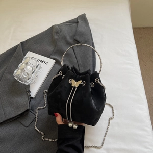 Detail of black velvet bucket bag featuring silver butterfly clasp and pearl drawstring