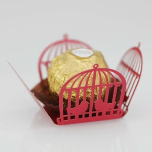 Macro shot of red laser-cut birdcage chocolate holder with detailed bird silhouettes