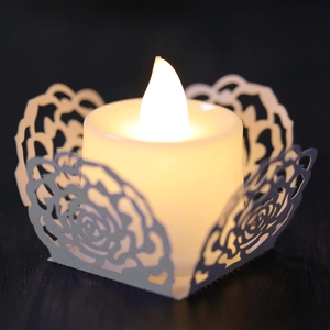 Nahaufnahme eines LED-Teelichts mit weißer, lasergeschnittener Rosendekorhülle aus Papier