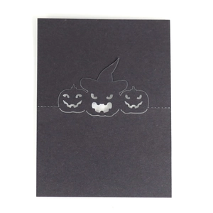 Detail of laser-cut black Halloween place card featuring pumpkins and wizard hat