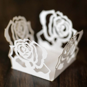 Makroaufnahme einer weißen lasergeschnittenen Rose-Papierbox auf dunklem Holz