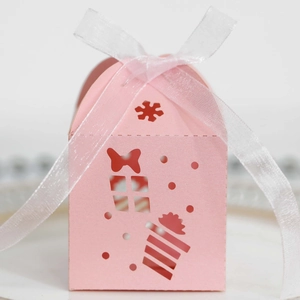Macro detail of pink house-shaped hollow Christmas gift box with ribbon and snowflakes
