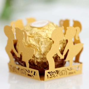 Macro detail of laser-cut gold cupcake wrapper featuring boy and girl silhouettes