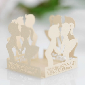 Close-up of laser-cut cream party favors showing intricate couple silhouette and rose lace
