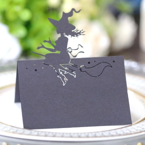 Halloween table card with black laser-cut witch riding broom silhouette on ceramic plate