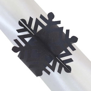 Macro detail of laser-cut black snowflake napkin ring with intricate hollowed patterns