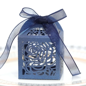 Detail of laser-cut rose patterns on dark blue pearlescent candy box with chiffon ribbon