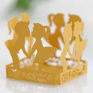 Detail of laser-cut golden paper candy box with boy and girl silhouettes and rose patterns