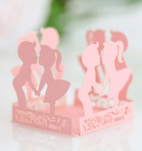 Macro shot of pink laser-cut paper favor box with boy and girl kissing silhouettes