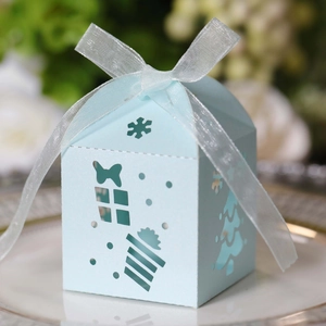 Detailed laser-cut snowflake and Christmas tree patterns on light blue gift box with ribbon