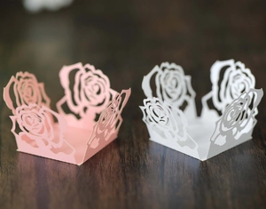 Makroaufnahme von lasergeschnittenen Rosen-Papierförmchen für Hochzeitsbonbons und Deko