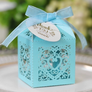 Macro detail of laser-cut heart pattern gift box with blue ribbon and thank you tag