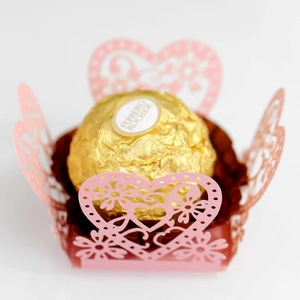Macro view of laser-cut light pink heart candy wrapper with intricate floral details