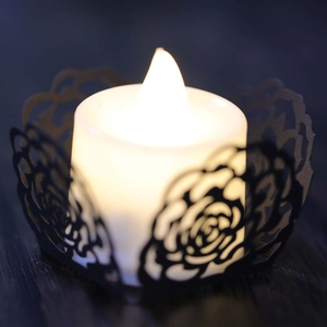 Detail der lasergeschnittenen schwarzen Rosen-Kerzenhülle mit warmem LED-Lichtschein