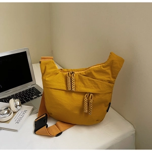 Detail of yellow nylon dumpling bag featuring dual zippers and woven rope pulls