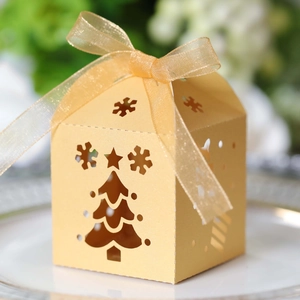 Detail of laser-cut gold Christmas tree gift box with shimmering ribbon and snowflake patterns