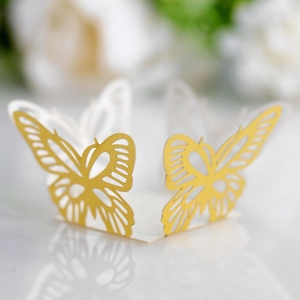 Macro view of delicate laser-cut gold and white butterfly party favors for wedding decor