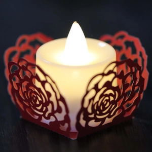 Makroaufnahme einer LED-Kerze mit roter Rosen-Laserschnitt-Hülle und warmem gelbem Licht