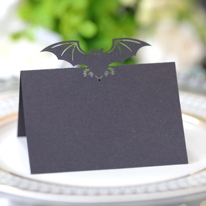 Laser-cut black bat place cards for Halloween table decoration on an elegant porcelain plate