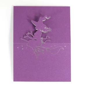 Macro detail of laser-cut purple witch silhouette card for Halloween table setting