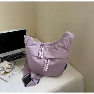 Detail of purple canvas crossbody bag with double zippers and stylish woven pullers