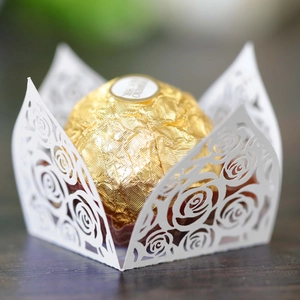 Detail of laser-cut white paper lace wrapper with rose patterns for wedding candy decoration