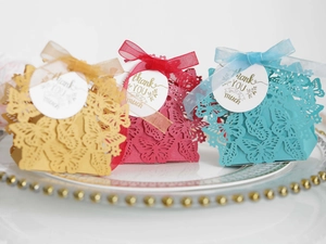 Detail of laser-cut butterfly gift boxes with ribbons and Thank You tags on a plate