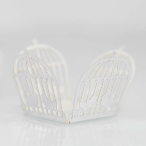 Macro detail of laser-cut white paper wedding favor box with romantic birdcage pattern