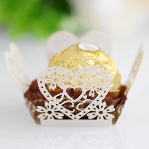 Macro shot of white laser-cut paper chocolate holder with heart and floral hollow patterns