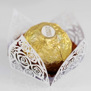 Macro shot of white laser-cut rose lace paper wrapper holding a chocolate truffle