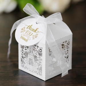 Detail of laser-cut Eiffel Tower favor box with white ribbon and thank you tag