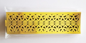 Close-up of golden hollowed-out napkin ring with intricate vine texture and shiny finish