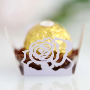 Nahaufnahme der lasergeschnittenen weißen Rosen-Papierhülle für Schokoladendekoration