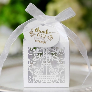 Close-up of laser-cut Eiffel Tower white favor box with satin ribbon and thank you tag