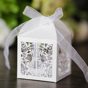 Detail of laser-cut white Eiffel Tower candy box with elegant ribbon for wedding favors